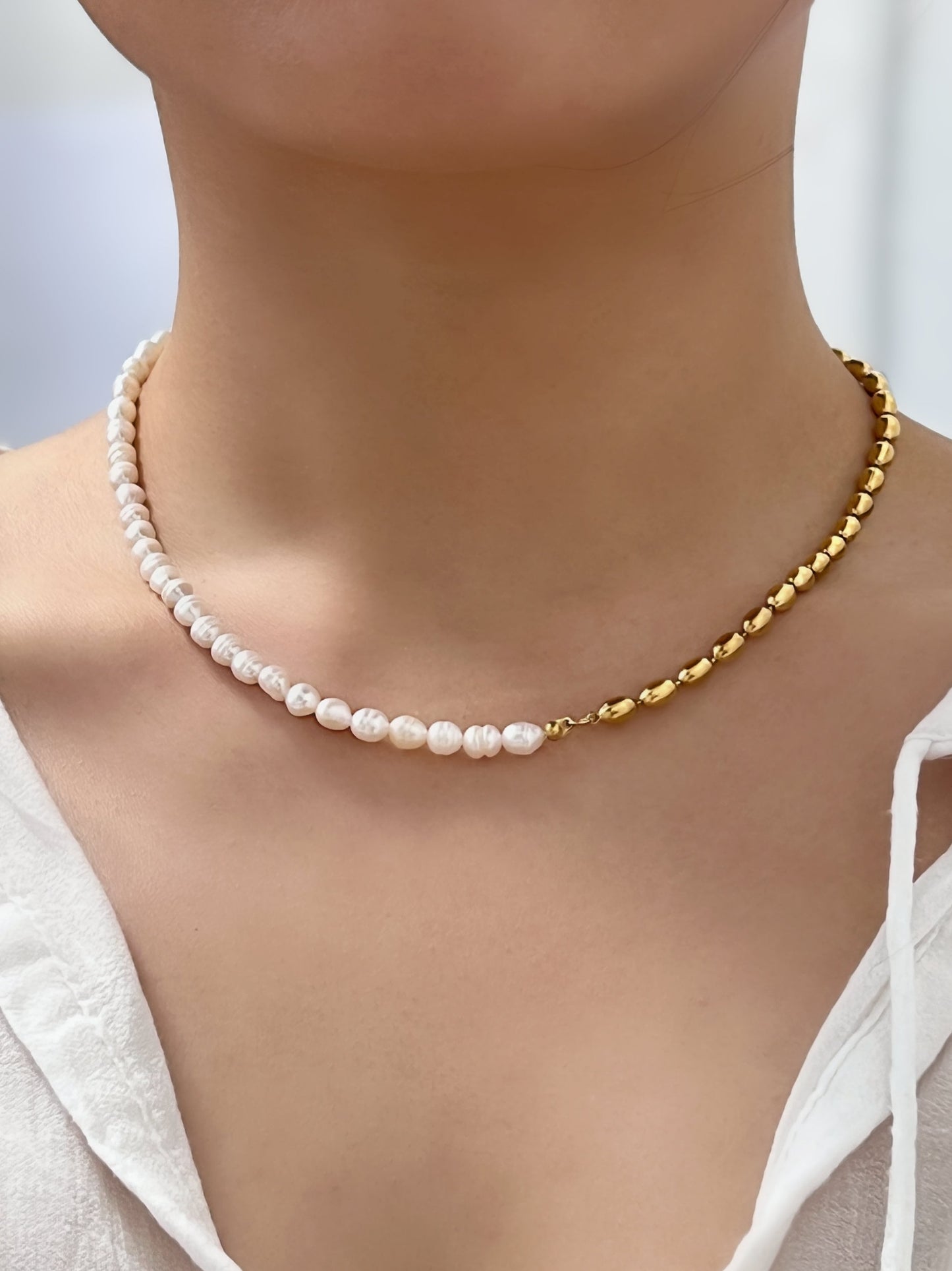Woman neckline displaying the modern look of a singular asymmetric baroque pearl strand close up