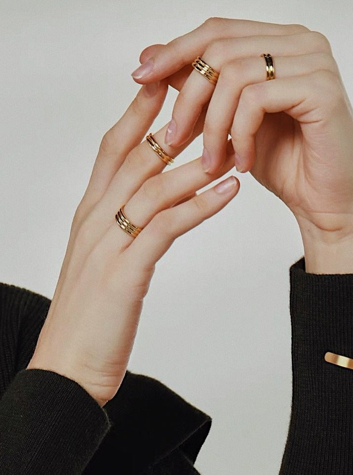 Close up of hand stacking gold fluted rings in slim and thick