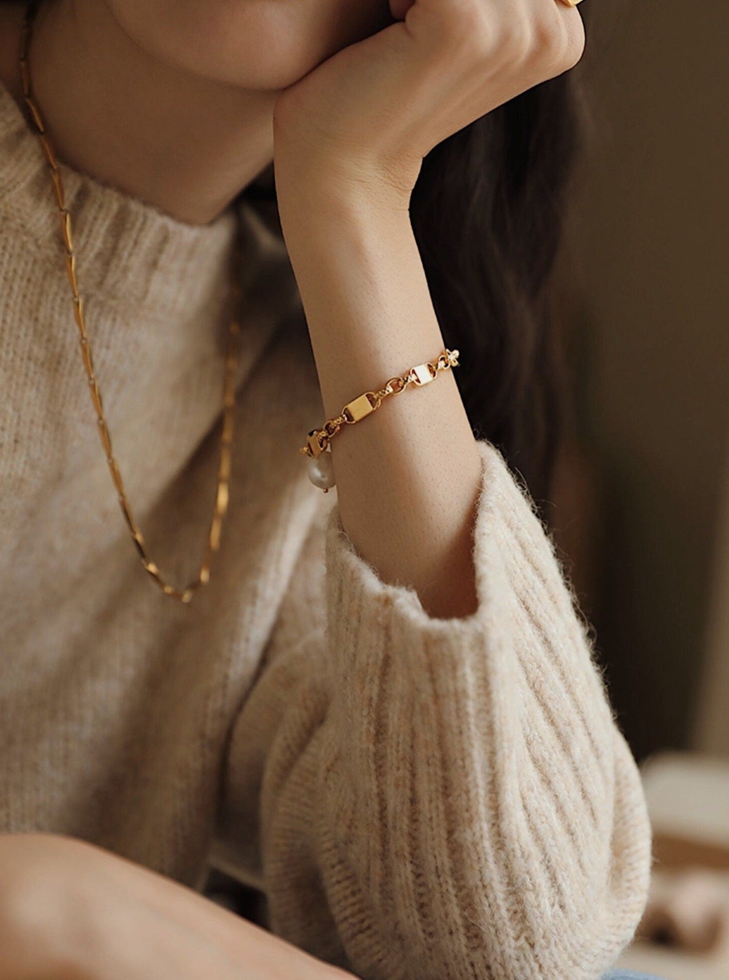 A soft-focus portrait showing the Diana gold pearl chain bracelet draped elegantly below the wrist bone for an elevated wardrobe look.