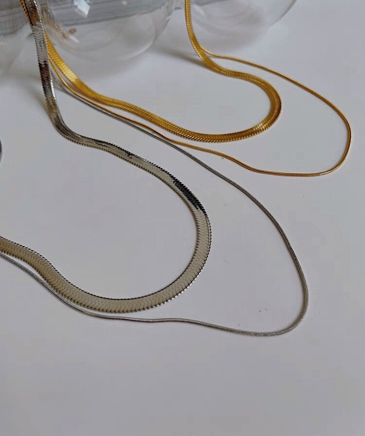 Elegant warm yellow gold double layer necklace resting neatly alongside cool silver double chain necklace