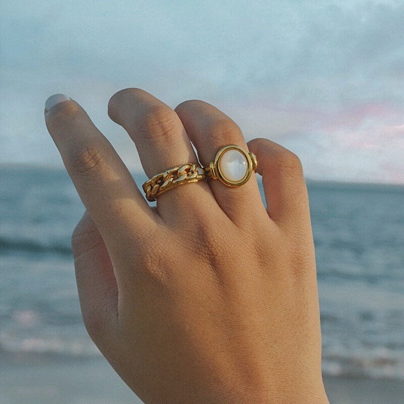Lifestyle shot of gold ocean-ready ring on hand at beach australia