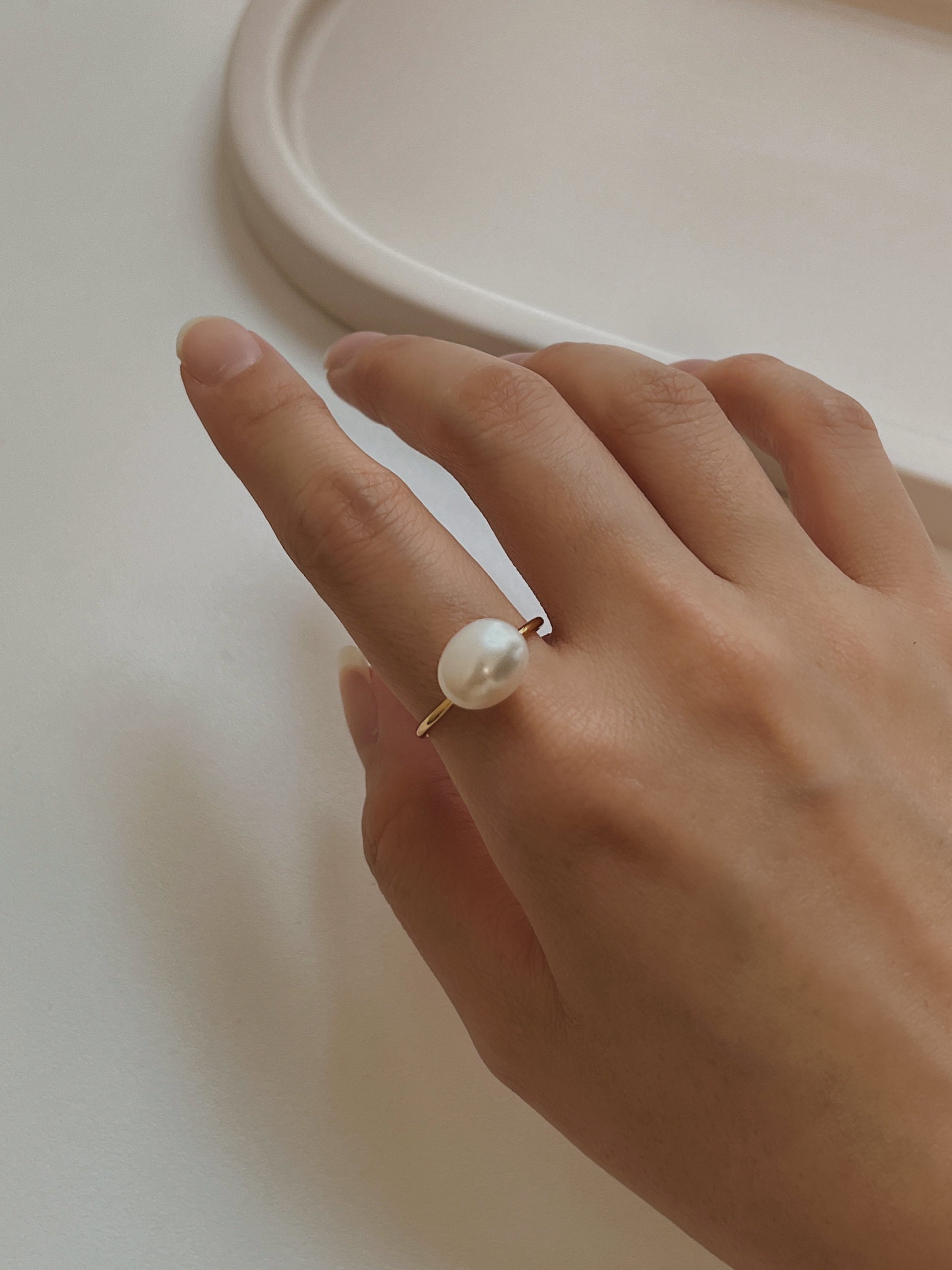 Hand model wearing Vivienne baroque pearl ring on index finger