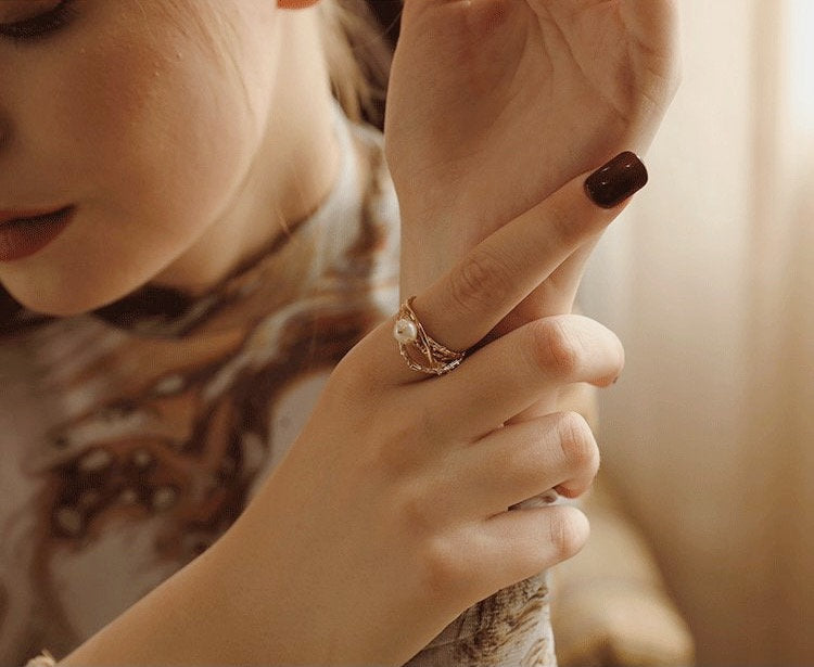 Modern heirloom pearl ring on hand model with a dark color manicure