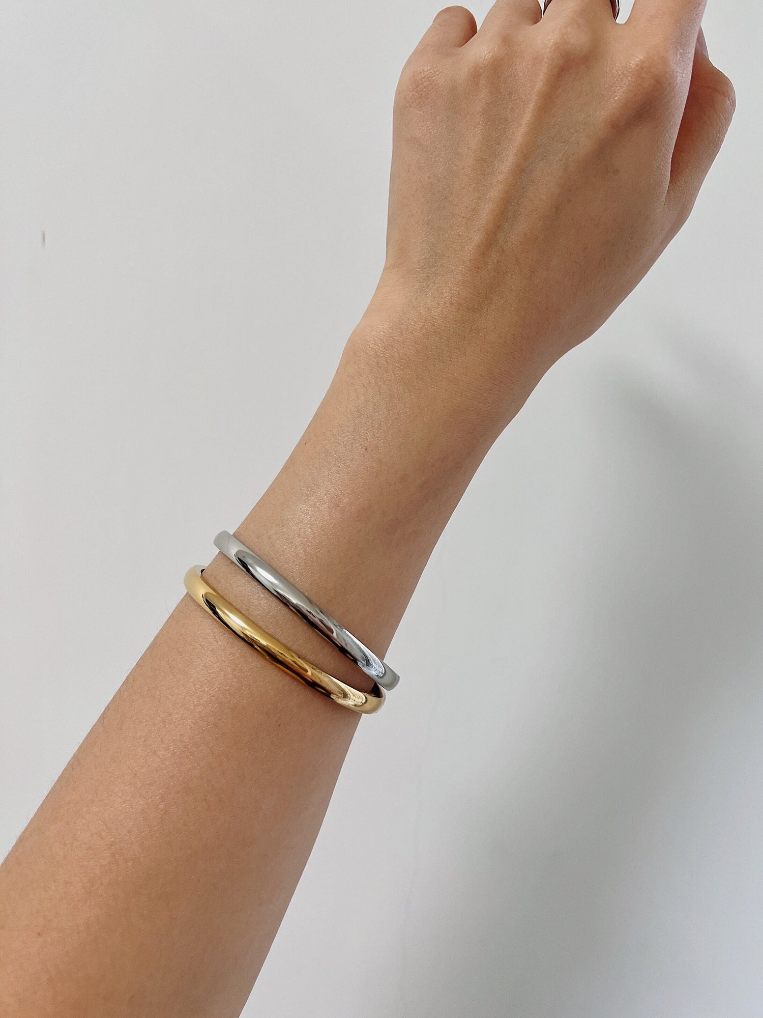 Elegant gold and silver bangle bracelets on wrist, perfect for stylish jewelry lovers.