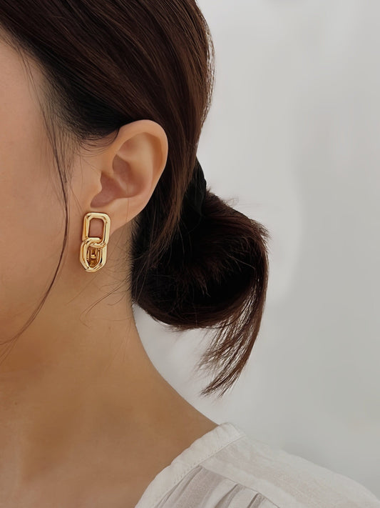 Gold geometric link earrings on a woman's ear, stylish and modern jewelry piece.