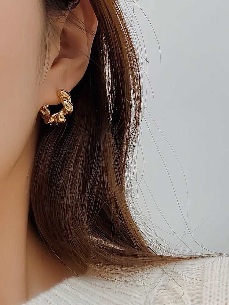 Close up of woman's ear featuring a pair of stunning 18K gold twisted hoop earrings for everyday