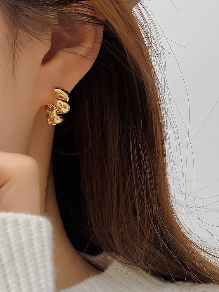 Close up of woman's ear featuring a pair of stunning 18K gold twisted hoop earrings for everyday