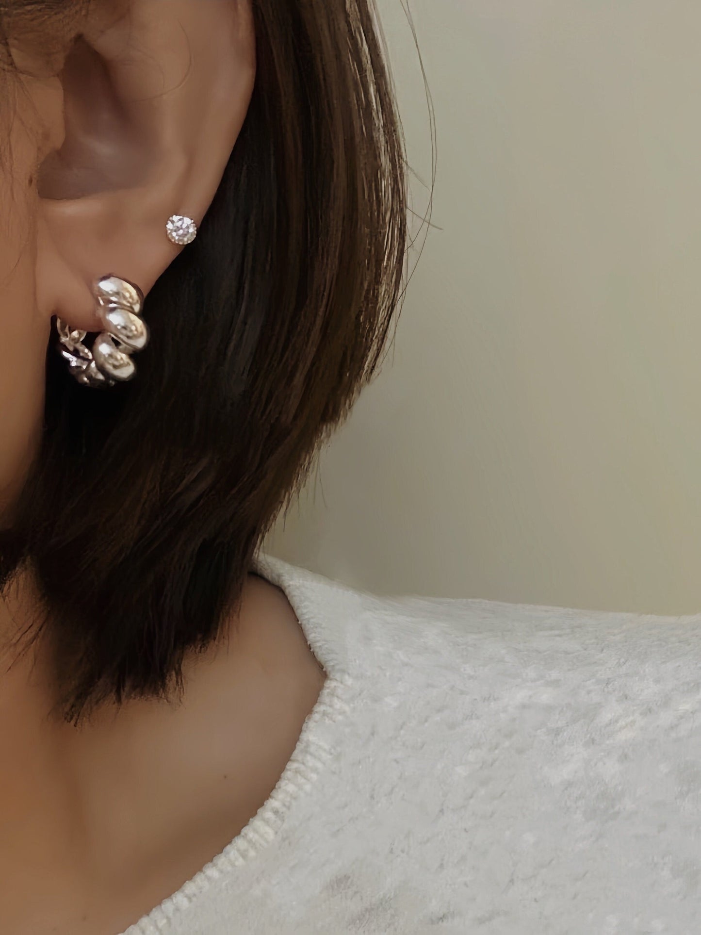 Close up of woman's ear featuring a pair of stunning silver twisted hoop earrings for everyday