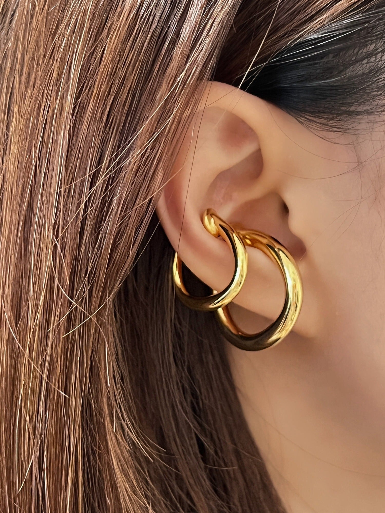 Stylish gold chunky ear cuff on model with brown hair, ideal for modern jewelry collections.