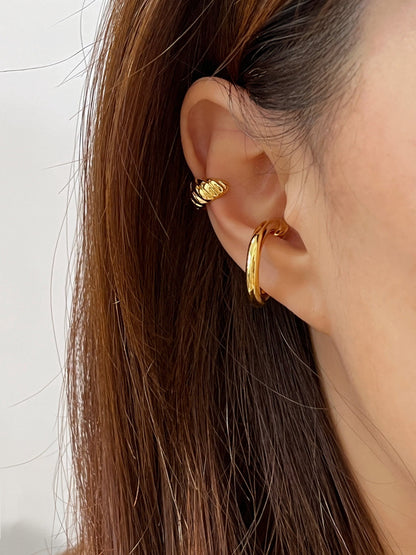 Close-up of gold ear cuff on model, showcasing trendy jewelry for fashion-forward individuals.