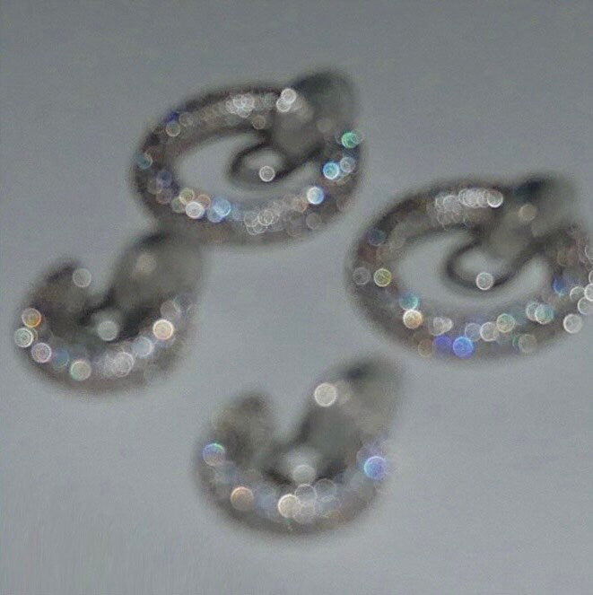 Light sparkles reflecting off rhodium plating and pavé cubic zirconia of Jayne clip-on hoop earring