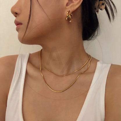 Woman wearing Lola double herringbone gold chain necklace on collarbone, white top, minimal editorial styling