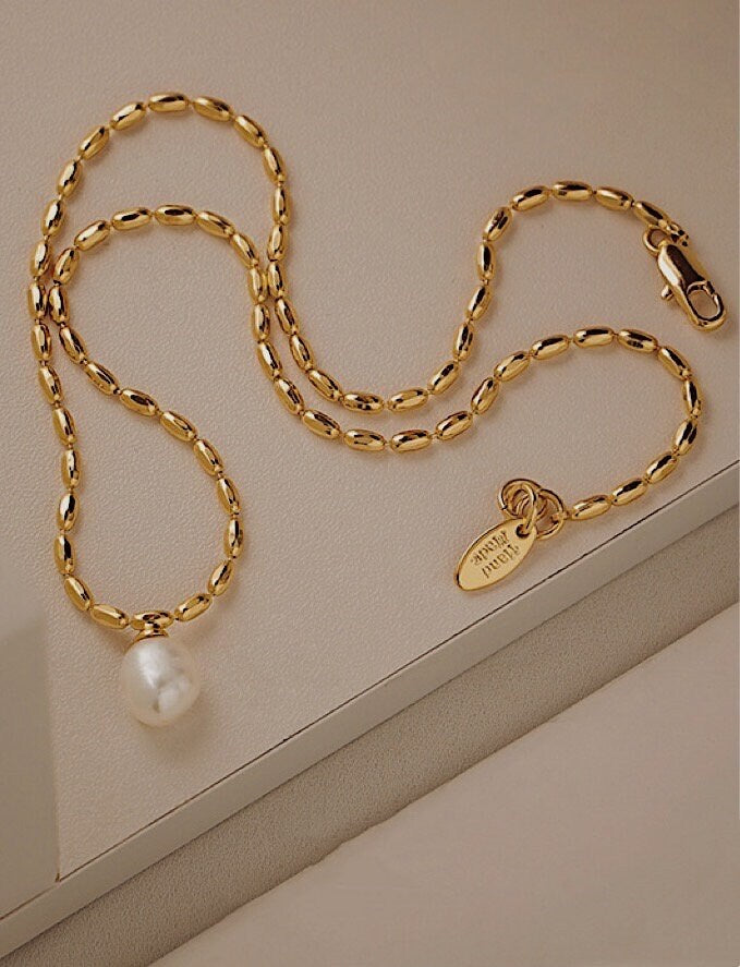 Marjorie gold bead pearl necklace displaying elongated liquid gold rice beads on a minimalist background tray