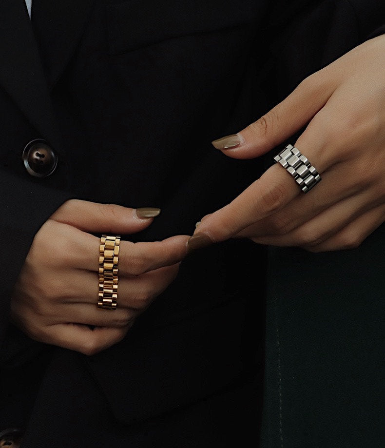 Luxe stack of gold and silver watch link rings on a hand model