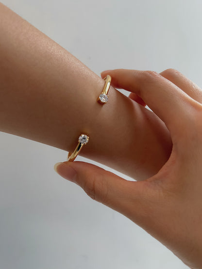 A model using her fingers to gently adjust the fit of the gold-plated Justine crystal cuff bracelet on her wrist.