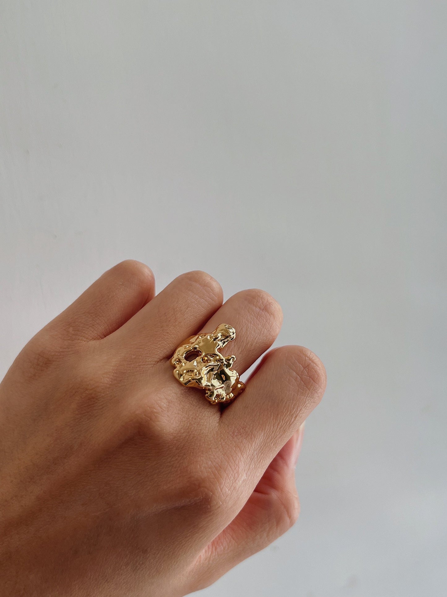 Hand styling an adjustable molten gold ring on the middle finger for a modern aesthetic