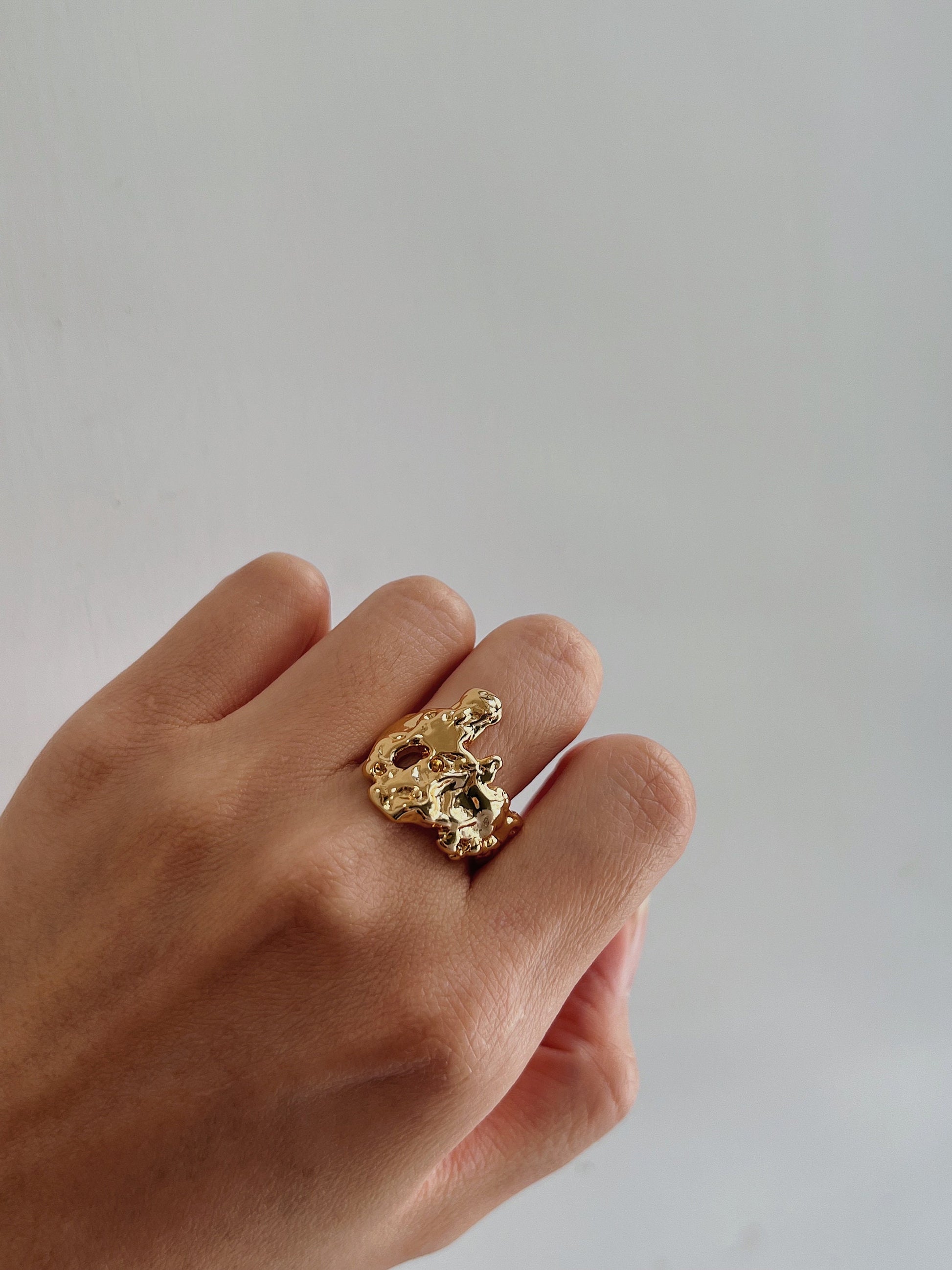 Hand styling an adjustable molten gold ring on the middle finger for a modern aesthetic