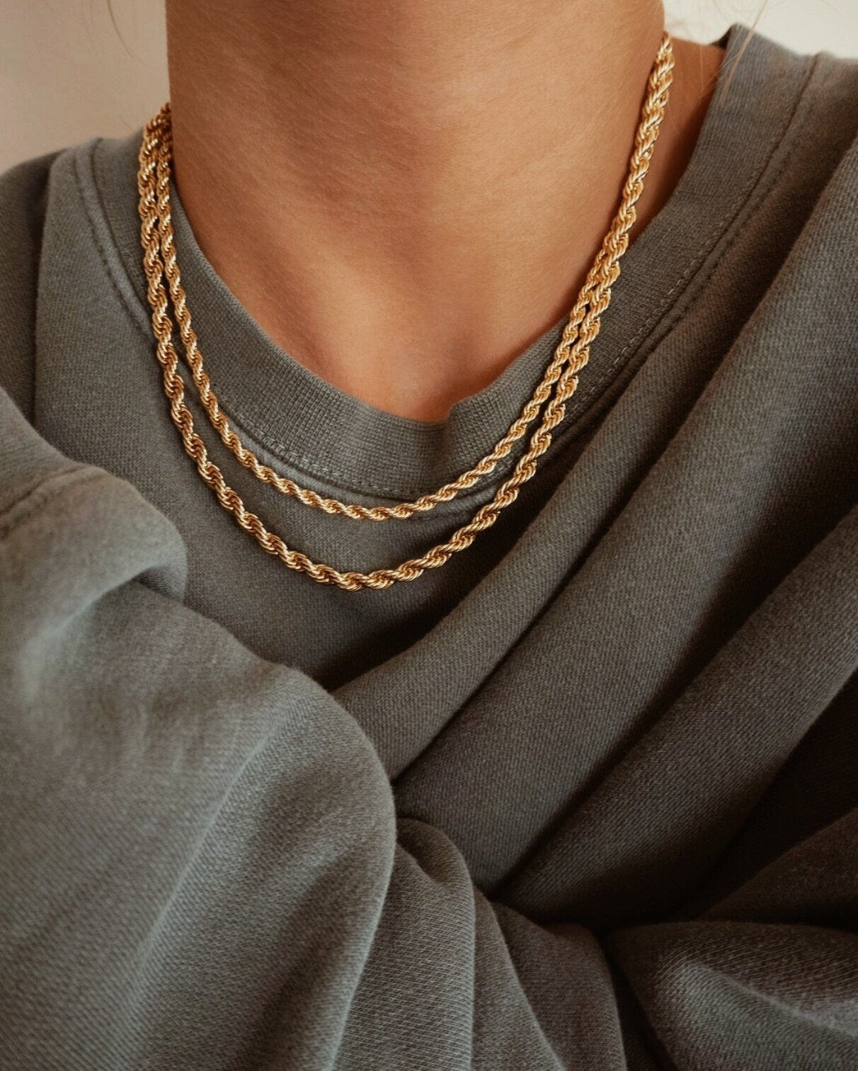 Model styling layered double strand gold twisted rope necklaces over grey sweatshirt apparel