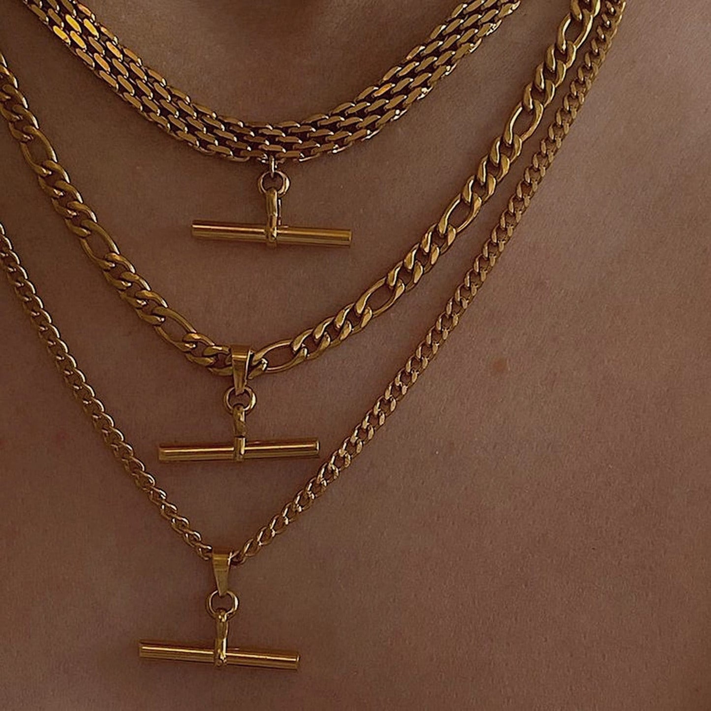 Model chest view styling multiple layered gold T bar pendant necklaces over skin