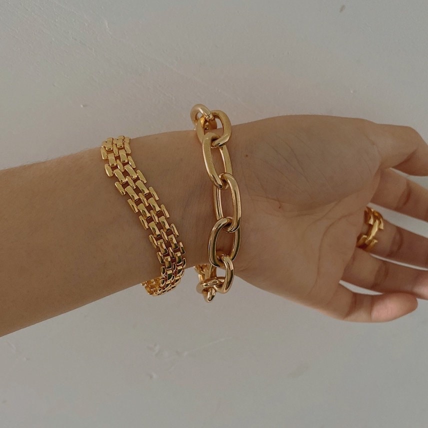 Woman wrist displaying the modern vintage look of a stacked gold brick link bracelet