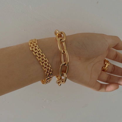 Woman wrist displaying the modern vintage look of a stacked gold brick link bracelet