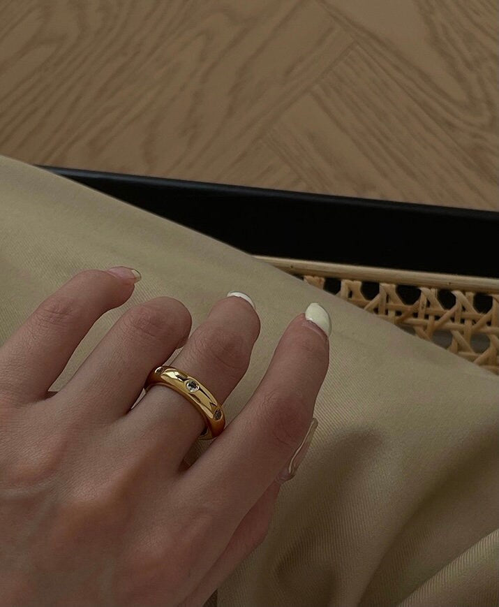 Hand styling a bold CZ gold statement ring on the middle finger
