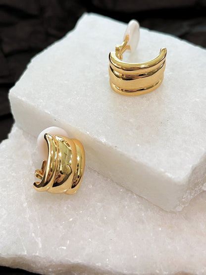 Pair of gold Molly vintage ribbed clip-on earrings displayed on white marble showing front ridges and white silicone cushion pad