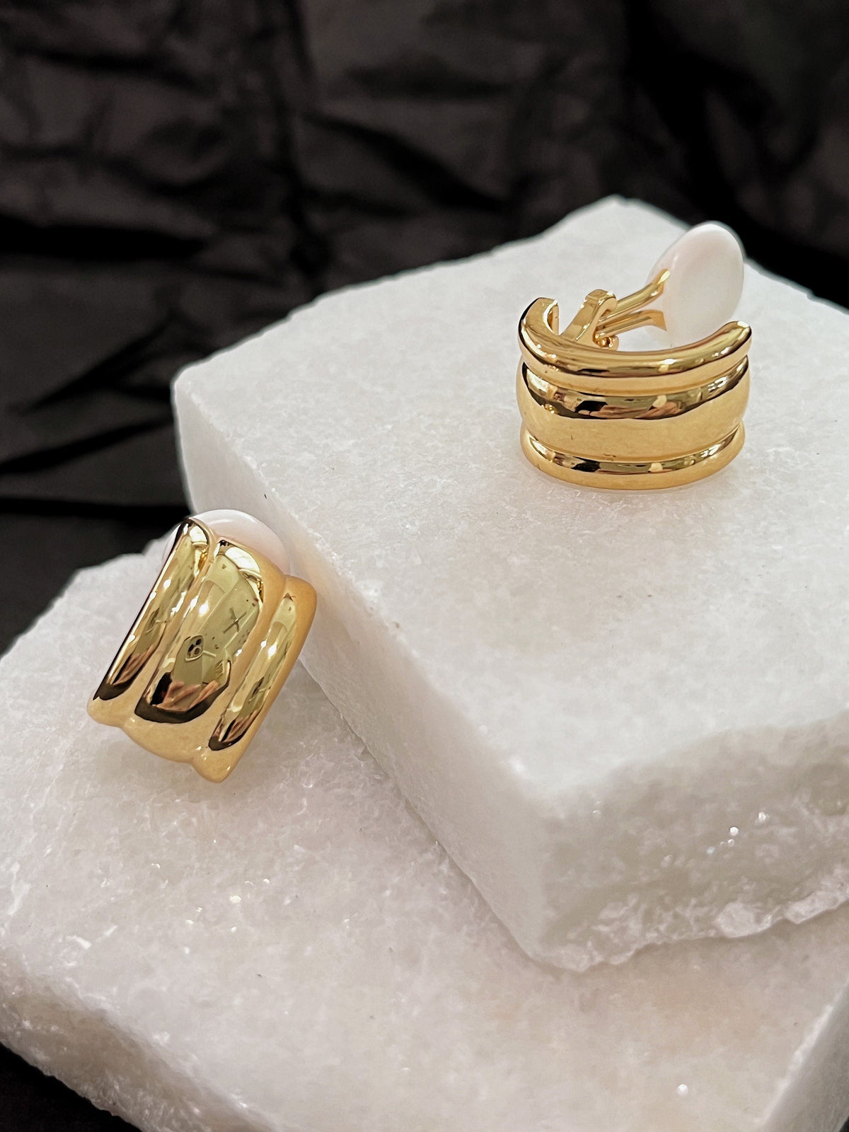 Pair of Molly 18k gold plated vintage ribbed clip-on earrings resting on white marble