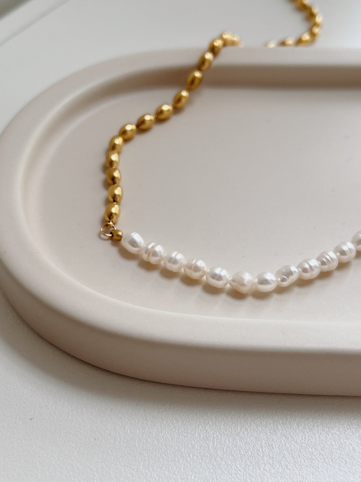 Contemporary luxury choker necklace displaying reflective irregular pearls on a minimalist display tray