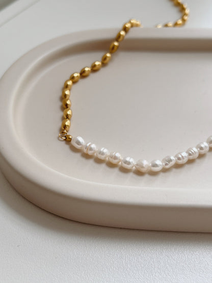 Contemporary luxury choker necklace displaying reflective irregular pearls on a minimalist display tray