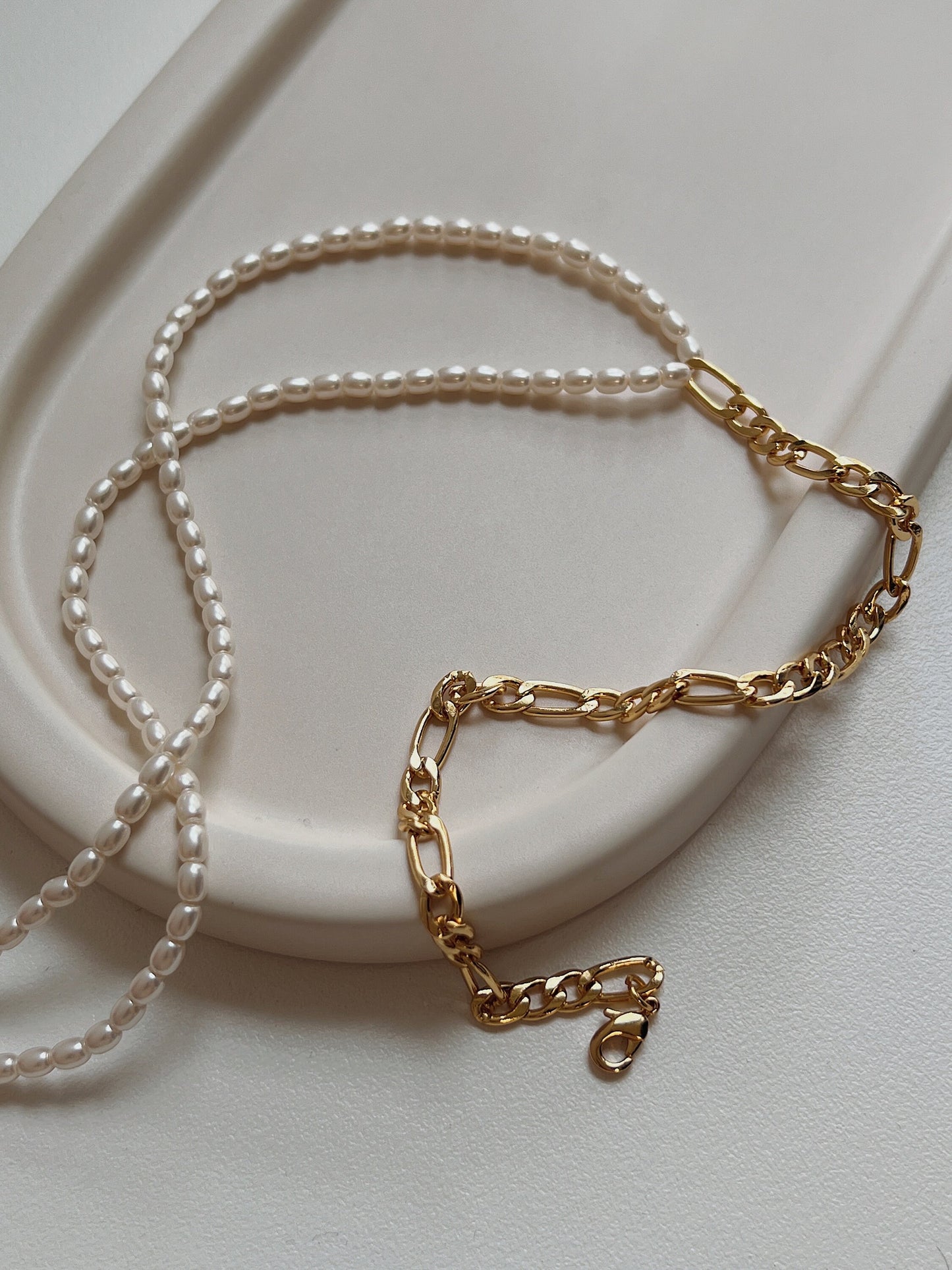 Asymmetrical gold mixed media necklace flat lay showing high luster seed pearls