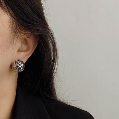 Model wearing a chunky rhodium silver lattice clip-on earring paired with a structured blazer and sleek long hair.