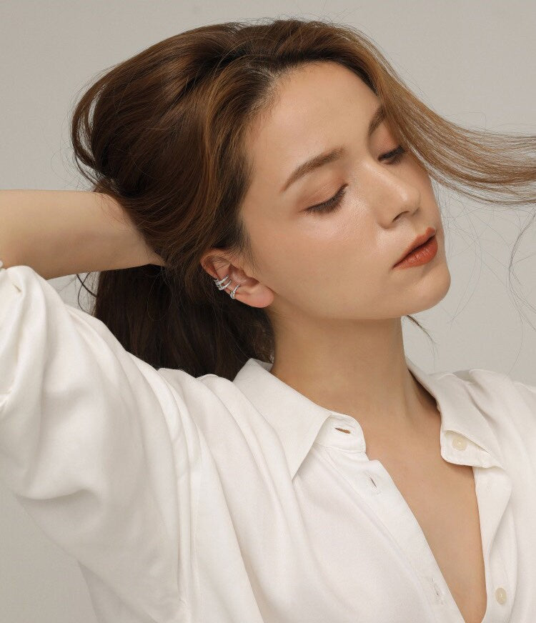 Lifestyle shot of a model styling a curated ear with gold pave cuffs.