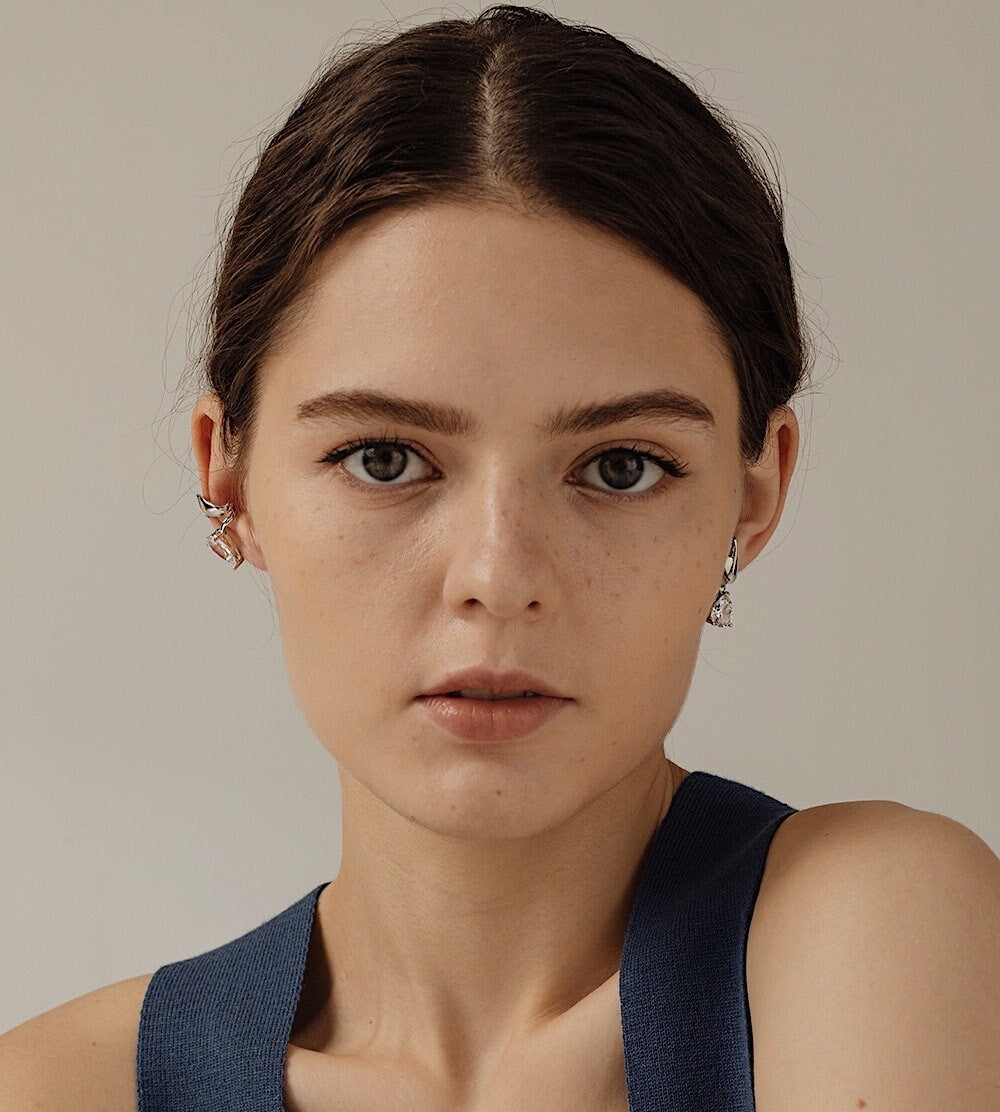 Model styling a set of Lisa Silver Cuff on mid-helix with sleek low pony hair.