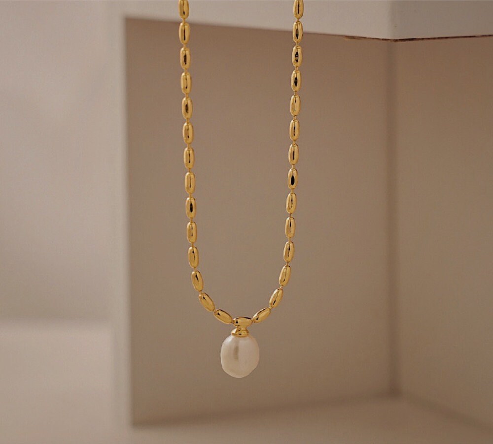 Close up view of a genuine organic freshwater pearl pendant suspended from an 18k gold pvd brass chain