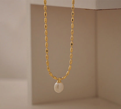 Close up view of a genuine organic freshwater pearl pendant suspended from an 18k gold pvd brass chain