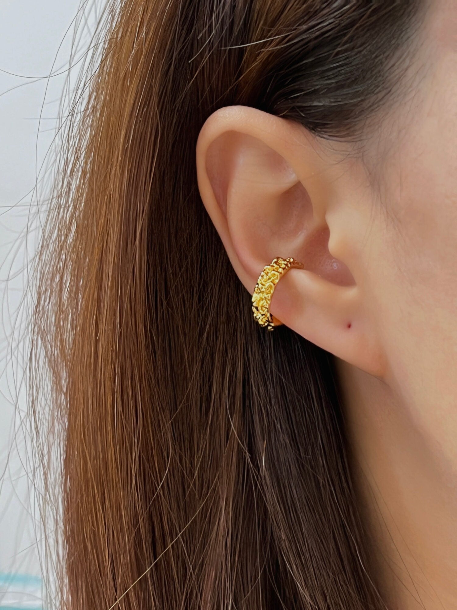 Model wearing the Molten Ridge gold PVD ear cuff with a sleek hair down hairstyle to highlight the ear stack.
