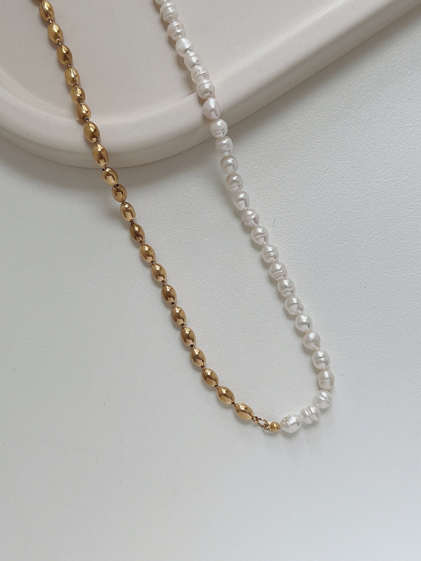 Close up view of asymmetric pearl strand transitioning into molten gold plated stainless steel elements