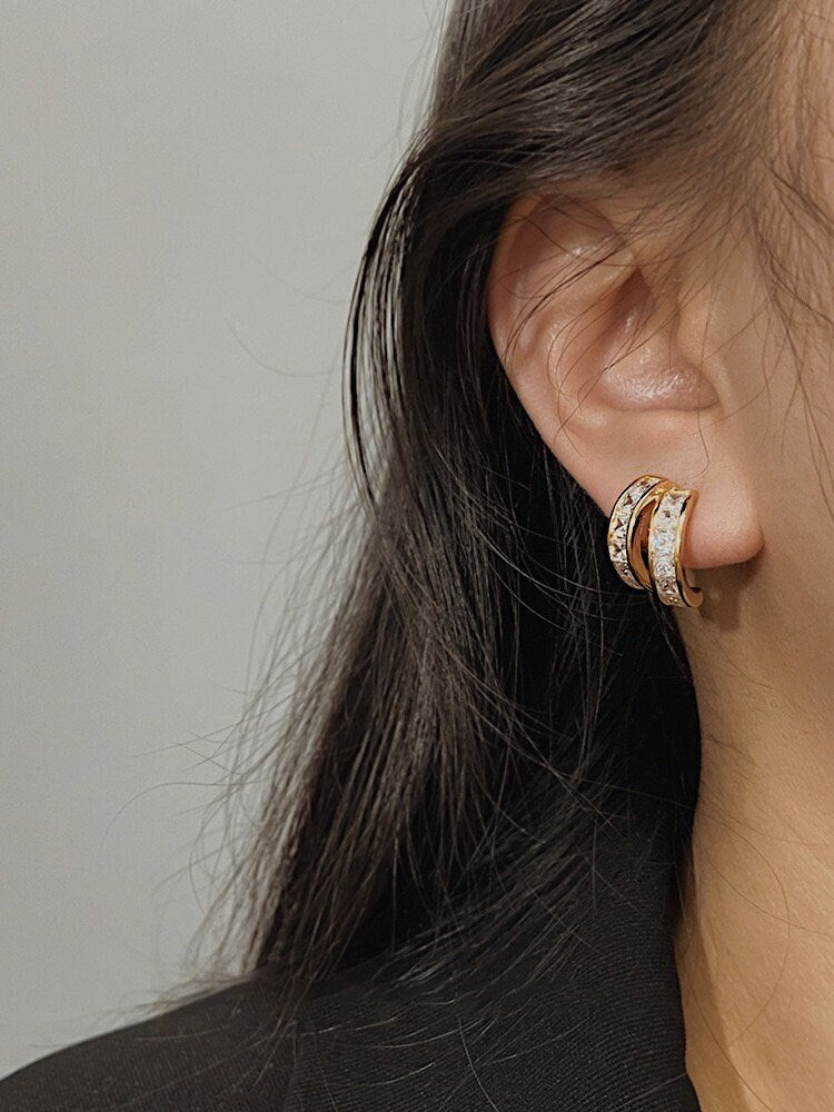 Model wearing Tiana princess cut gold clip-on earrings styled with black blazer