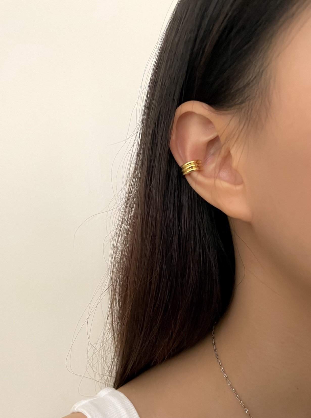Casual shot of a model styling the textured gold Elena cuff with a minimalist stack.