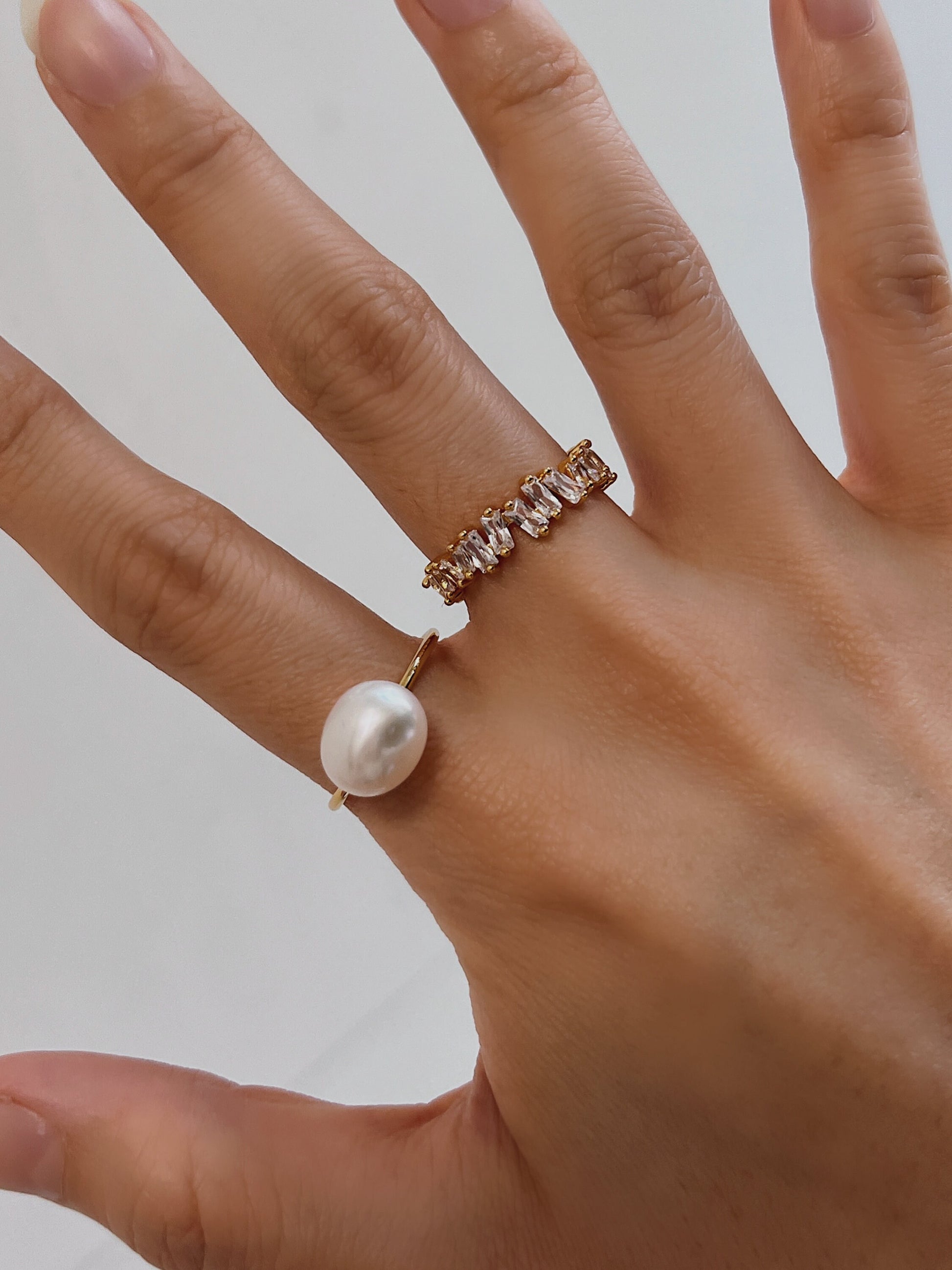 Hand model demonstrating the iridescence of Vivienne baroque pearl  and baguette ring
