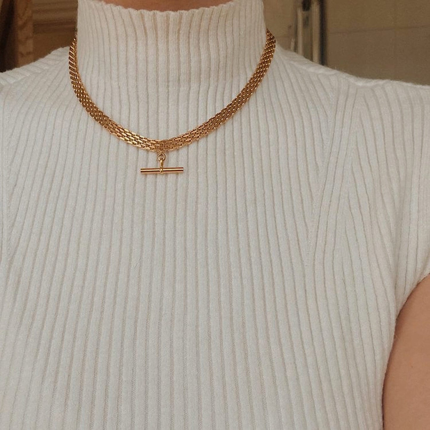 Woman neckline displaying modern 18k gold PVD stacked hardware chains placement look