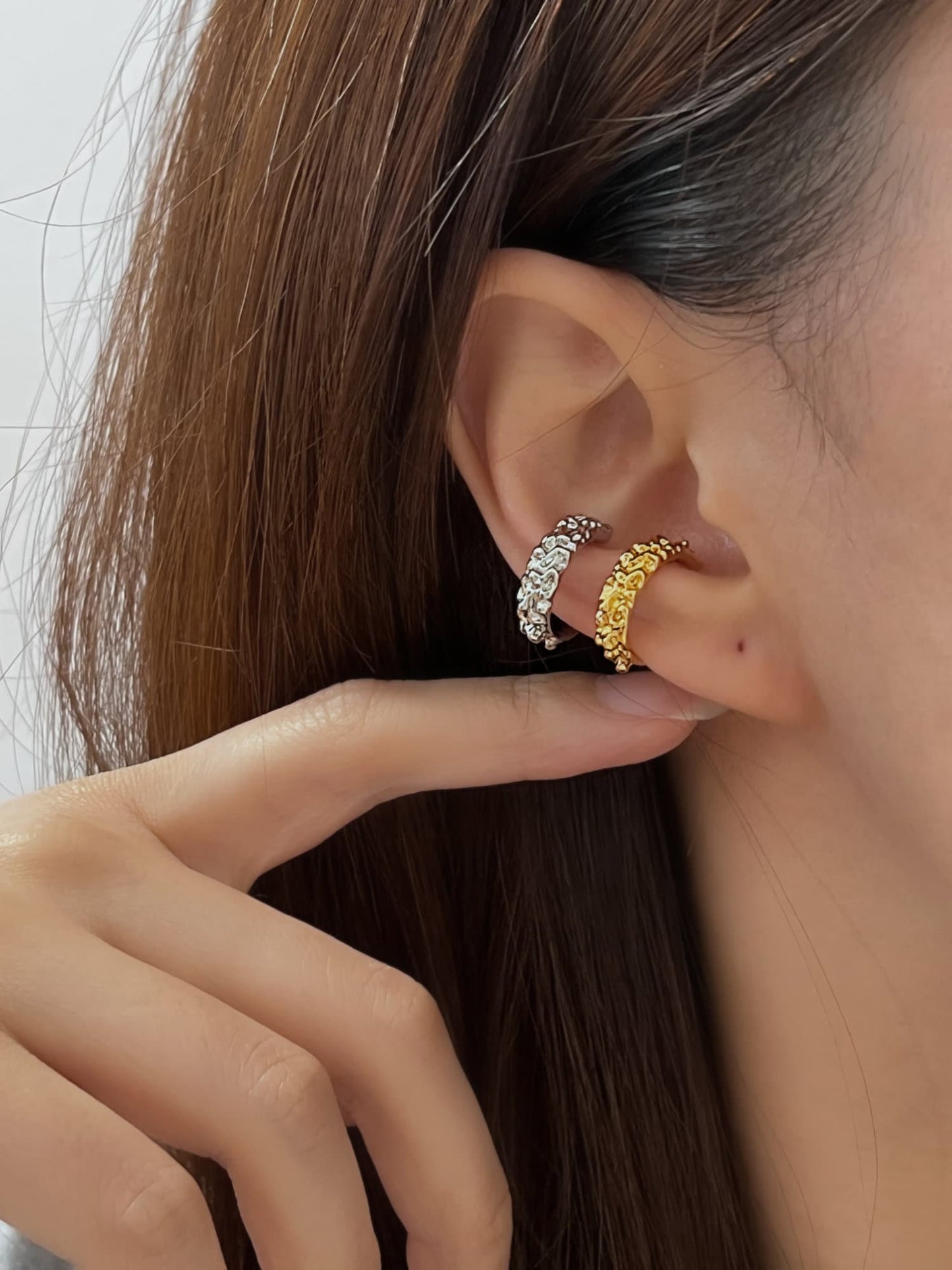 Close-up of model's ear showing the organic, sculptural fit of the Molten Ridge cuff.