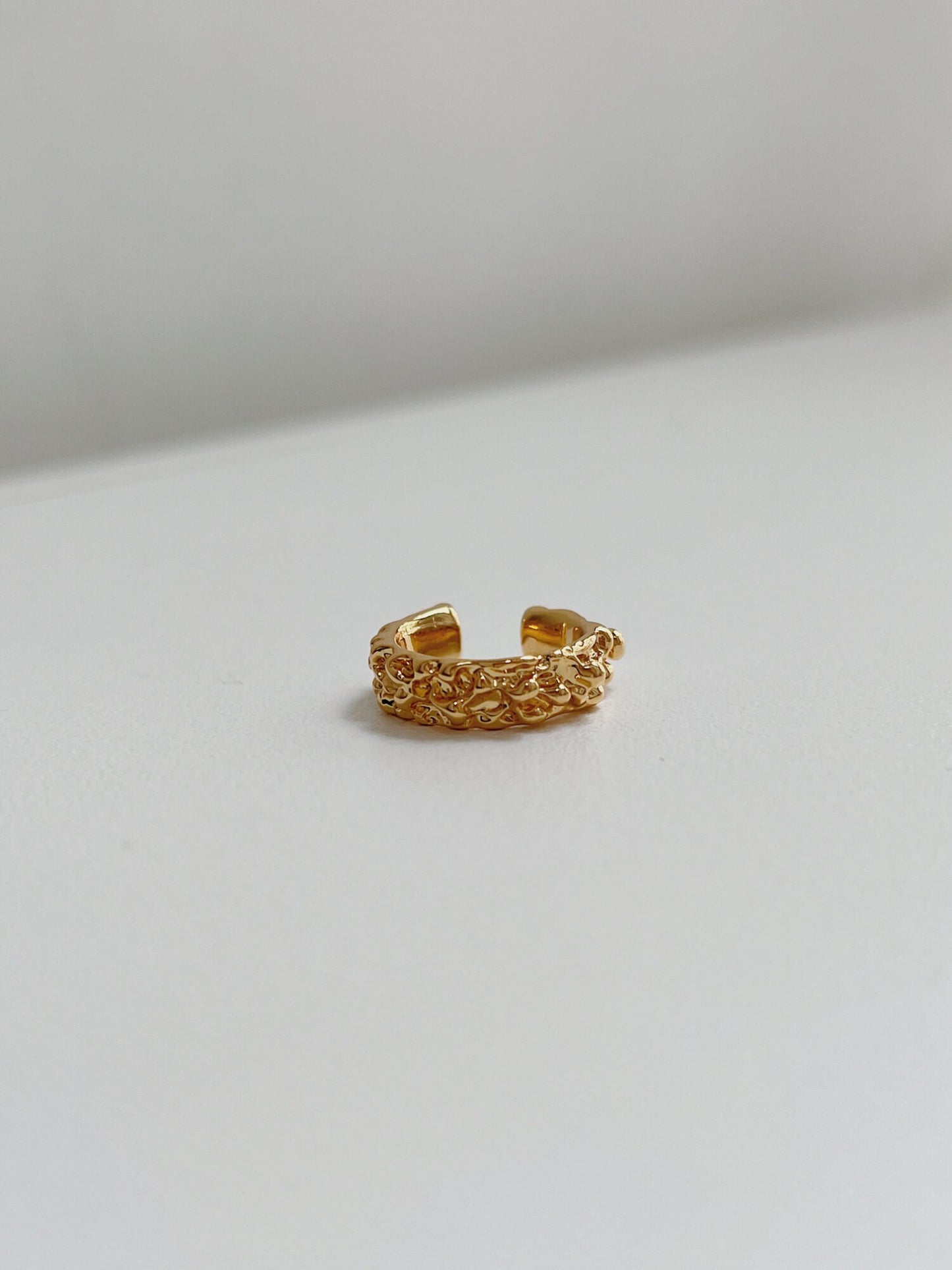 Detail view showing the architectural, wide-band silhouette of the gold Molten Ridge ear cuff.