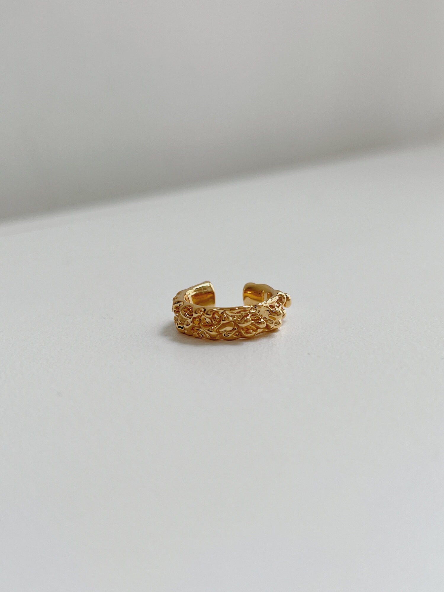 Detail view showing the architectural, wide-band silhouette of the gold Molten Ridge ear cuff.